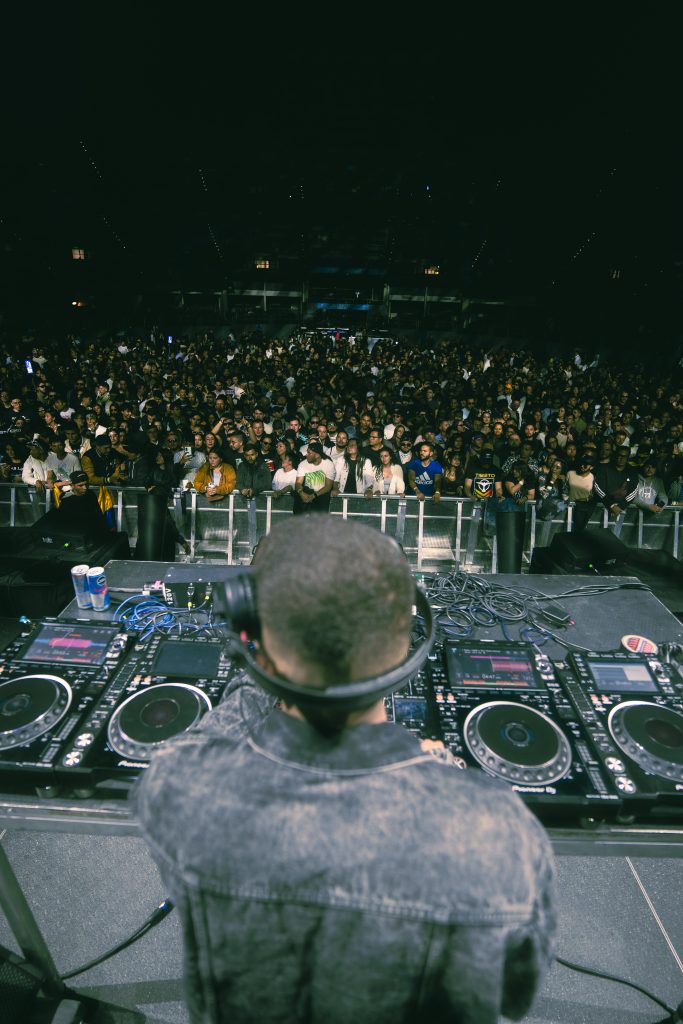 Vista desde cabina de Dezko durante presentación en festival, con multitud reunida frente al escenario principal.