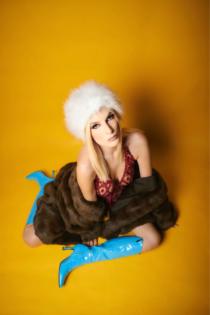 Fotografía de prensa de Niza, DJ argentina radicada en México, con look de plumas y pedrería para el lanzamiento de "Coming Up" en 2026.