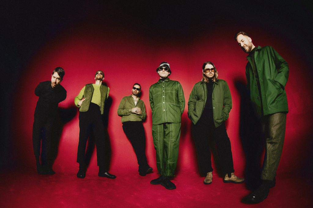 LEISURE en fotografía de prensa 2025 para el álbum 'Welcome To The Mood', con los seis integrantes del colectivo de Auckland frente a fondo rojo.