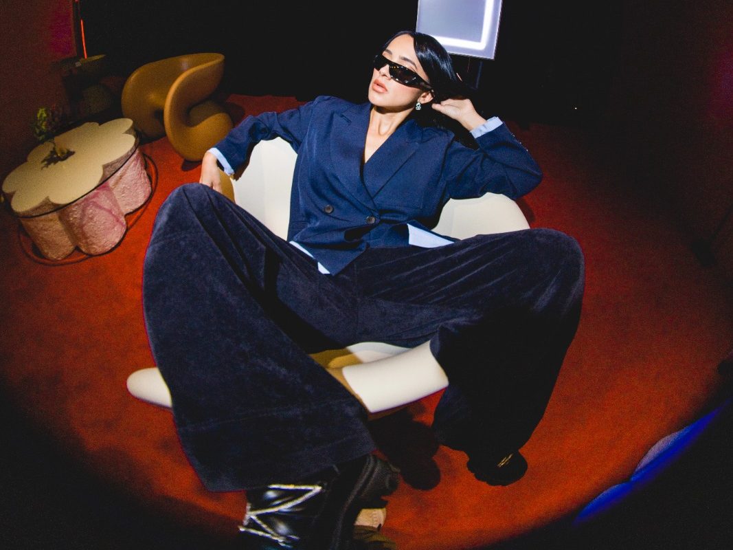 CiCiBi con cabello azul en sesión fotográfica editorial dentro de una lavandería, estética alternativa y urbana.