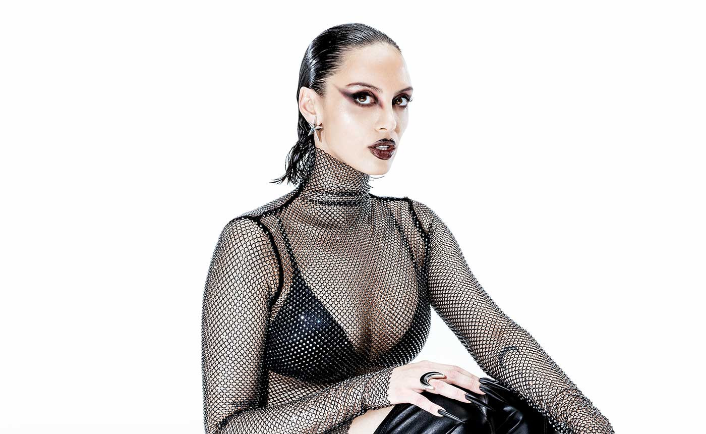Sara Landry, DJ y productora de hard dance techno, posa en fotografía oficial para su gira Eternalism 2026. Fondo oscuro, expresión concentrada, cabello negro liso.