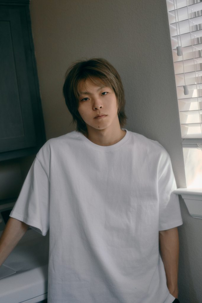 Kensuke Sorematsu, líder de KID PHENOMENON, posa con camiseta blanca durante una sesión fotográfica.