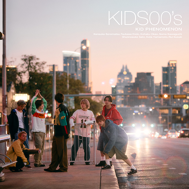 Portada de KIDS00’s, segundo álbum de KID PHENOMENON, con los siete integrantes del grupo en una calle al atardecer.