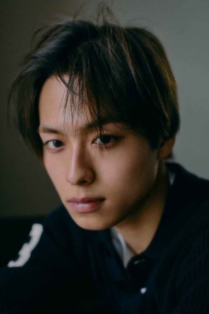 Soma Kawaguchi de KID PHENOMENON posa sentado con camisa de cuadros durante una sesión fotográfica.
